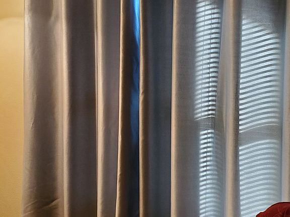 Blinds closed with freshly cleaned drapes and a red soft chair.