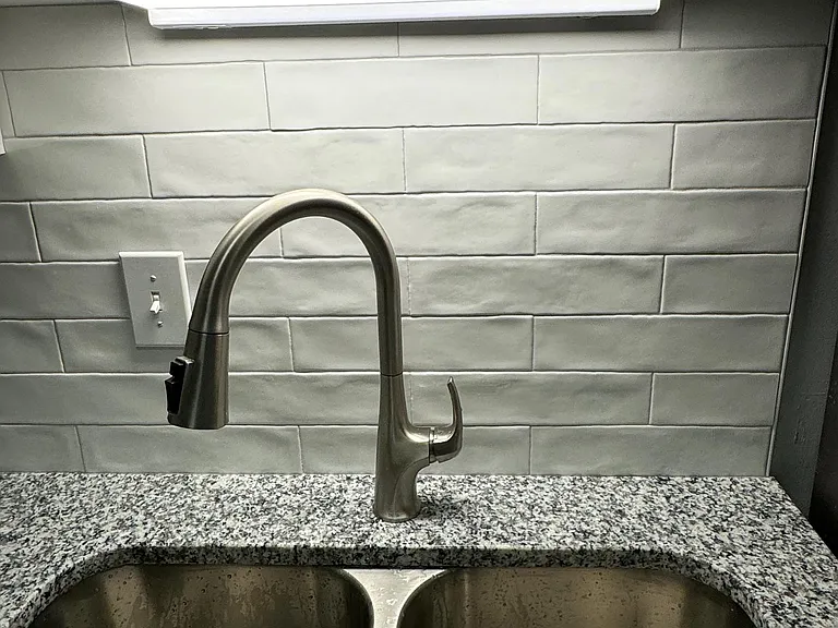 NEW SINK WITH DISPOSAL, FAUCET, AND CUSTOM SUBWAY TILE BACKSPLASH.