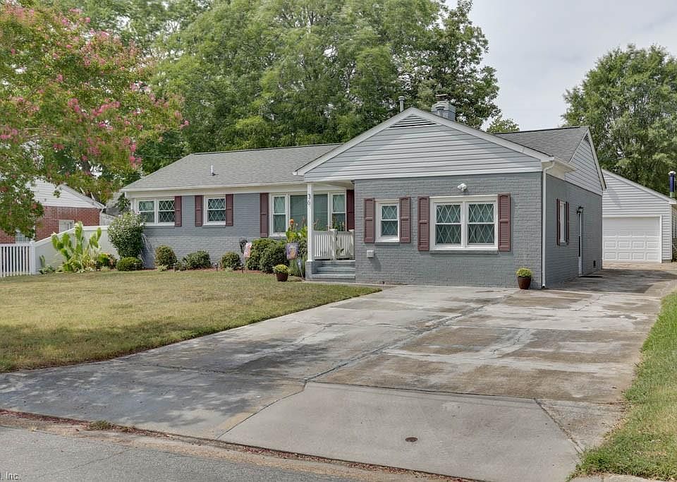 Beautifully landscaped yard with a peek of the detached garage & driveway space