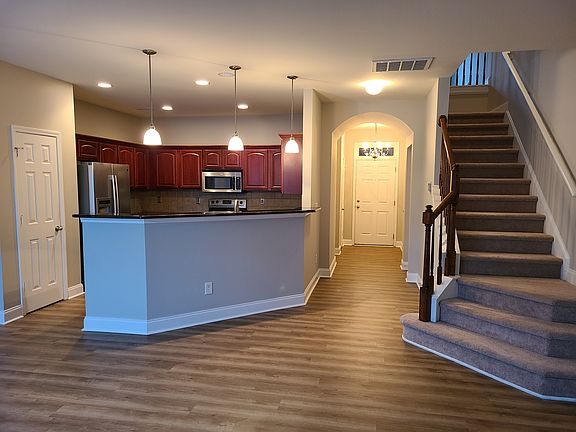 Overview from living room of entrance with kitchen and stairs. Powder room is under the stairs next to entrance