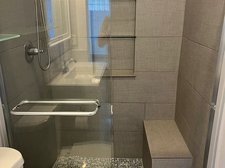 Shower has bench and wall storage area