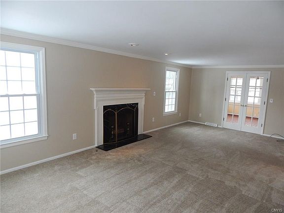 Front to back living room features gas fireplace and french doors open to heated sun room
