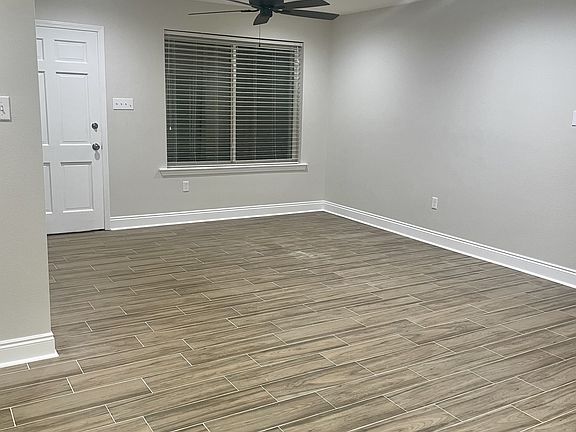 Spacious living area featuring brand-new flooring, fresh paint, ceiling fan, and updated lighting.