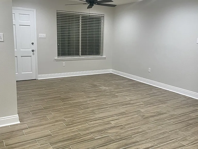 Spacious living area featuring brand-new flooring, fresh paint, ceiling fan, and updated lighting.