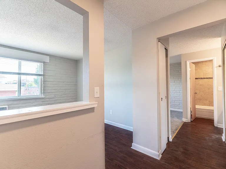Inviting apartment hallway with elegant laminate flooring and bright natural light, featuring a glimpse into a cozy bathroom.