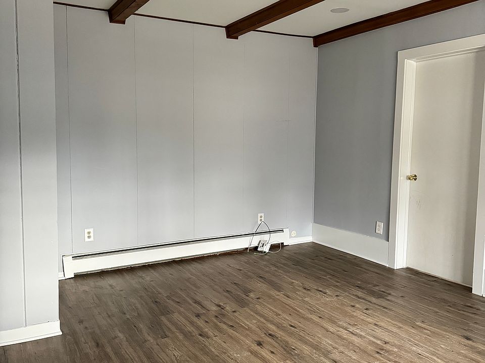 Combination living/dining room, newer paint, vinyl plank floors, decorative ceiling beams (bedroom door on right)