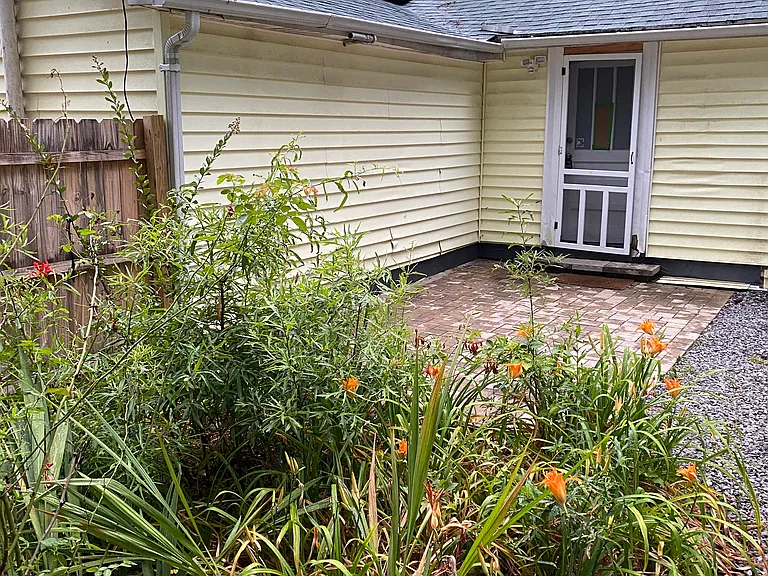 This is the primary door enterance. Parking is to the right of the paver patio. The sun sets on the front of the house so in the evenings is it pleasant to sit on the back porch and overlook the yard and garden area.