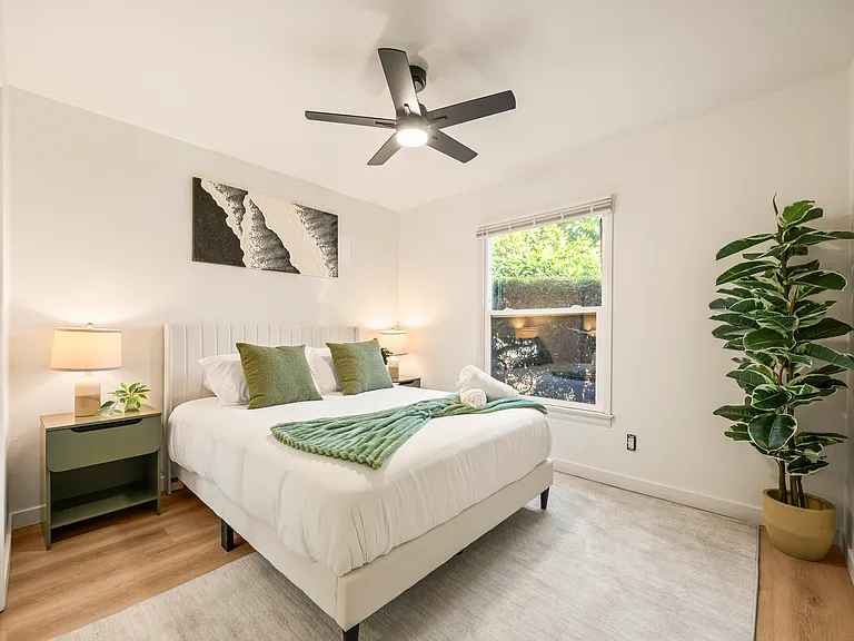 Cozy bedroom with a queen bed, ceiling fan, soft lighting, and comfortable accommodations designed for restful nights after exploring San Diego.