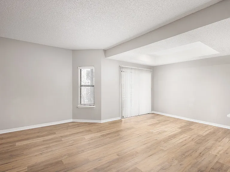 Bright and airy living space with elegant wood flooring and large windows featuring sleek blinds.