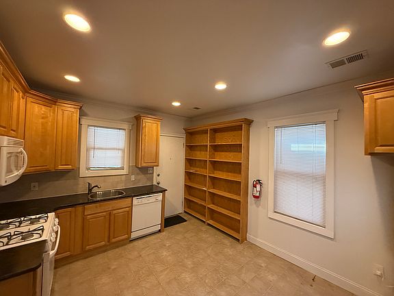 Kitchen with stove, refrigerator, dishwasher, microwave, built in storage, and access to back deck and backyard.