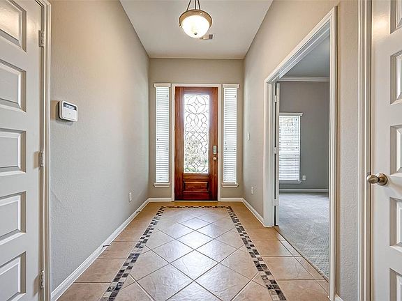 Lovely entryway with ceramic tiles with mosaic border. Notice the rich wood front door with ornate leaded window pane.