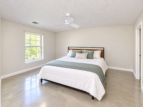 Primary bedroom with sealed concrete floors and celing fan.