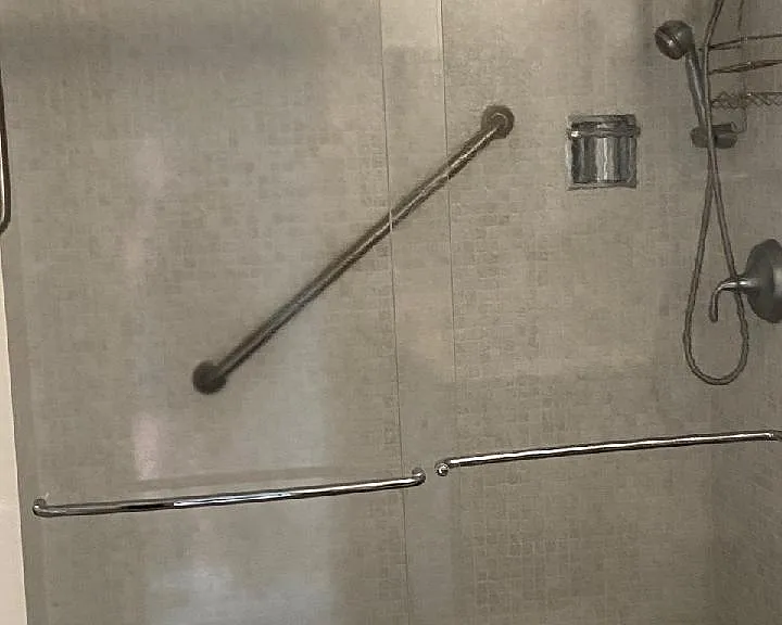 Tiled walk-in shower with Kohler cast iron shower base with safety tread. Grab gars, fixed and hand shower heads, sliding glass doors.