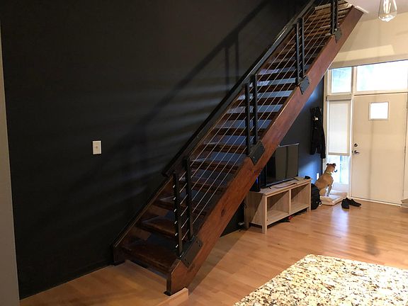 View from open kitchen to living room and private street entrance. Floating wooden staircase to bedroom.