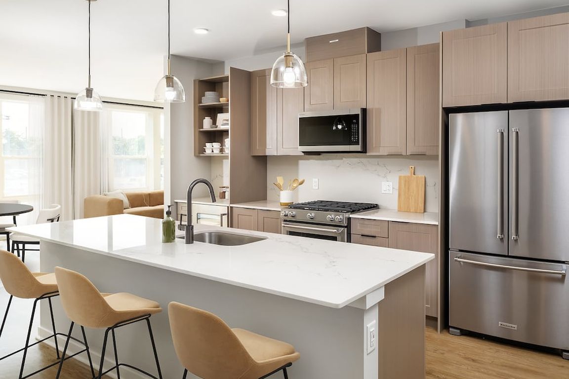 Signature Collection Kitchen with oak shaker cabinetry, marbled white quartz countertop, and upgraded stainless steel appliances