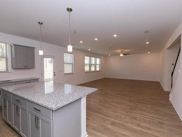 Spacious kitchen featuring an island, abundant storage, stainless steel appliances, and an open view into the living room.