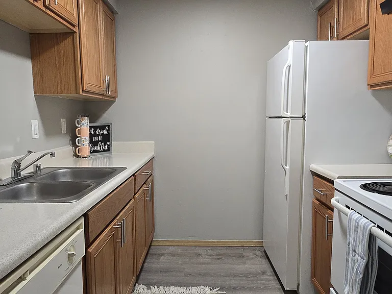 Cozy, functional kitchen with warm wood cabinetry, ample counter space, and white appliances. Features a double sink, efficient layout, and plenty of storage_perfect for everyday cooking.