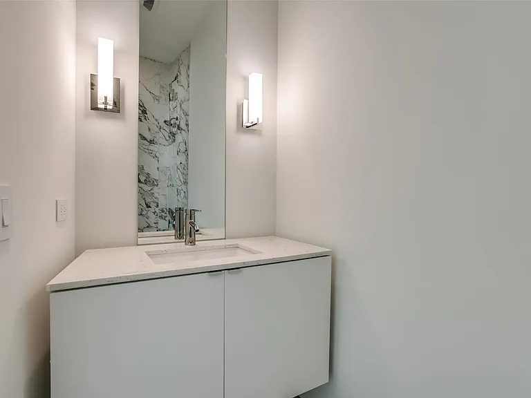Floating vanity with integrated sink and chrome faucet, flanked by two vertical sconces