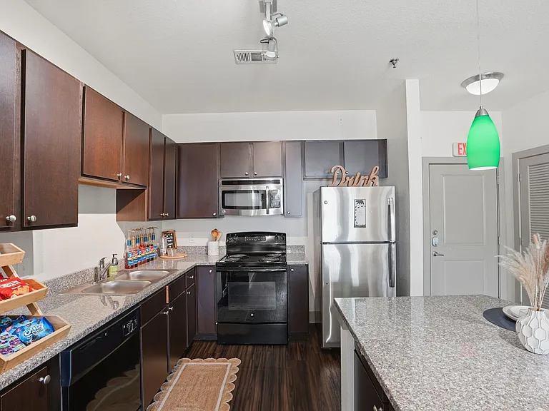 Modern kitchen with dark wood cabinets, sleek countertops, and stainless steel appliances.
