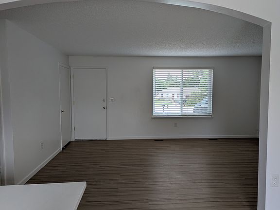 Living room with from kitchen with view of coat closet and front door.