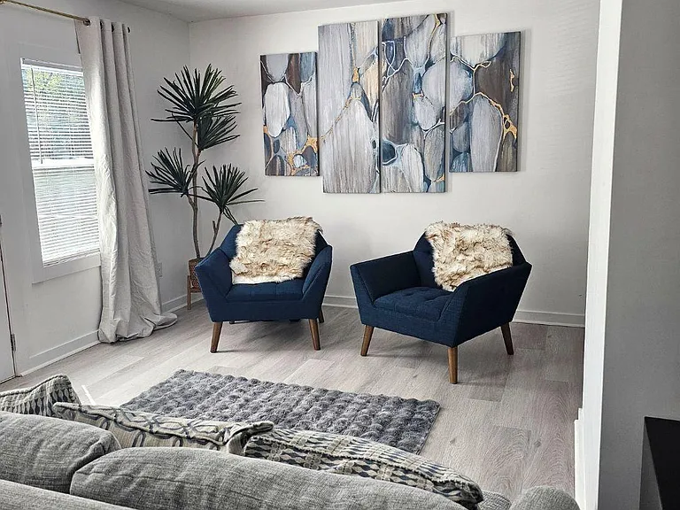 Comfortable living room with a seating area, recessed lighting, and a window with curtains for natural light.