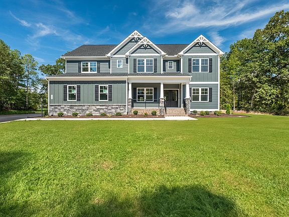 A large gray and white house with a gabled roof, reminiscent of Savannah, is surrounded by lush gree