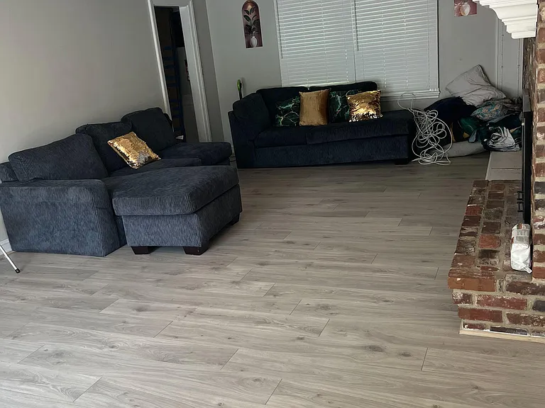 Spacious living room with recessed lighting, durable wood-look floors, and a brick fireplaceideal for relaxing or hosting.