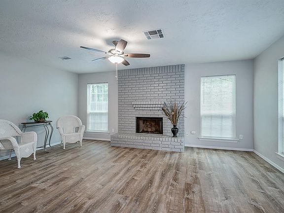 FAMILY ROOM with light grey walls, Beautiful Brick GAS LOG Fireplace, NEW FLOORS--WOOD LOOK, NEW BASEBOARDS, NEW Window BLINDS.