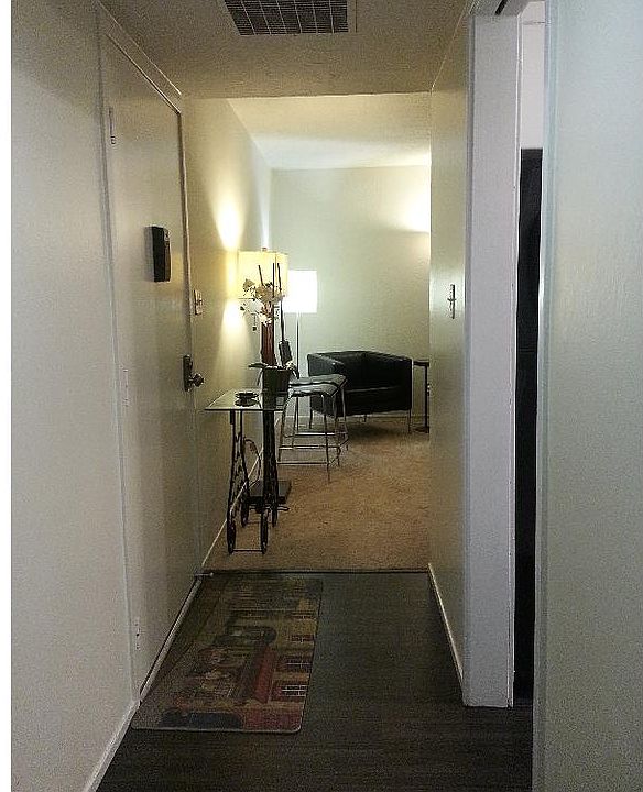 Hallway view of living room. Front door on left. Kitchen on