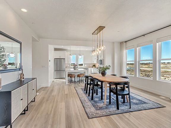 Modern dining area with wooden table and black chairs on a blue rug. The space features large window