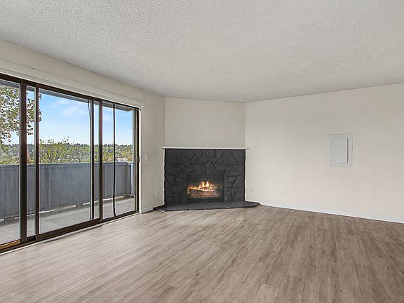 Warm and inviting living space featuring a cozy wood-burning fireplace, expansive sliding glass doors, and sweeping city views.