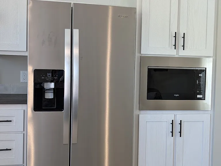 Side by side refrigerator with ice maker and water dispenser in door. Microwave.