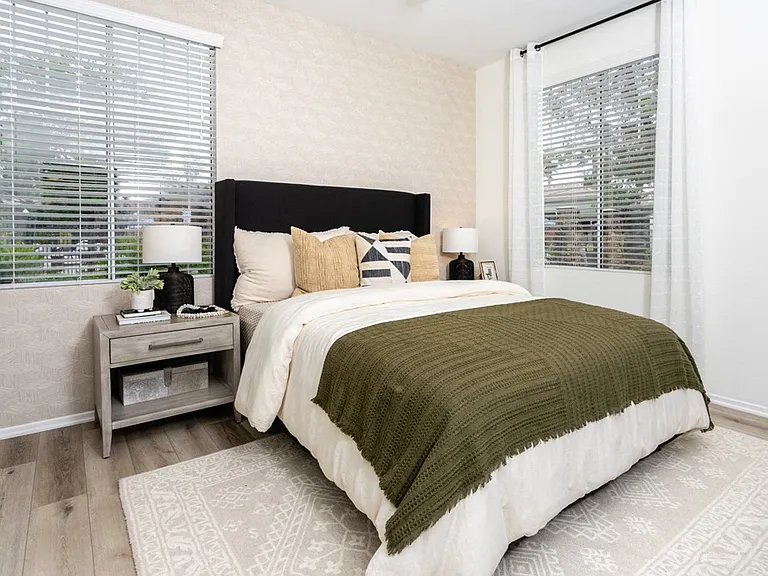 Spacious Bedroom Featuring Earth-Tone Decor and Large Windows with Blinds