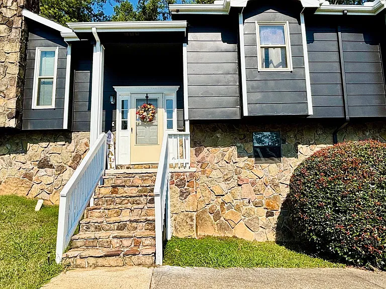 Welcoming front entry with stone steps, a covered stoop, and mature landscaping for great curb appeal.