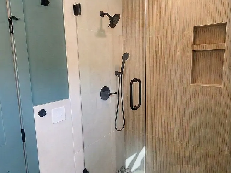 Lower bathroom shower with custom tile, shower nook, and modern glass enclosure