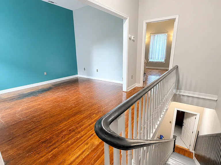 Private entrance with a bright stairwell, high ceilings, classic railing detail, and hardwood flooring.