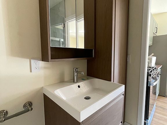 Spacious marble finish bathroom equipped with stylish wooden vanities and a tower closet perfect linen and towel storage