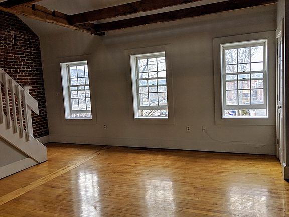 Bright and sunny living room, stairs to loft on left.