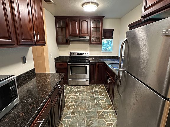 Bright, functional kitchen equipped with stainless steel appliances, including dishwasher, stove, oven, fridge, and microwave