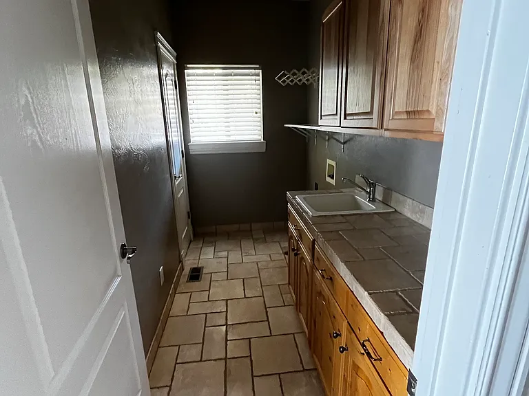 Laundry room includes countertop, cabinets, and storage closet.