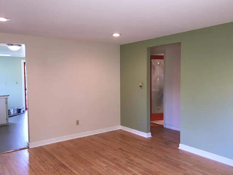 Unfurnished Livingroom, kitchen to left and bathroom/hallway to right. Fresh paint, all white living room.