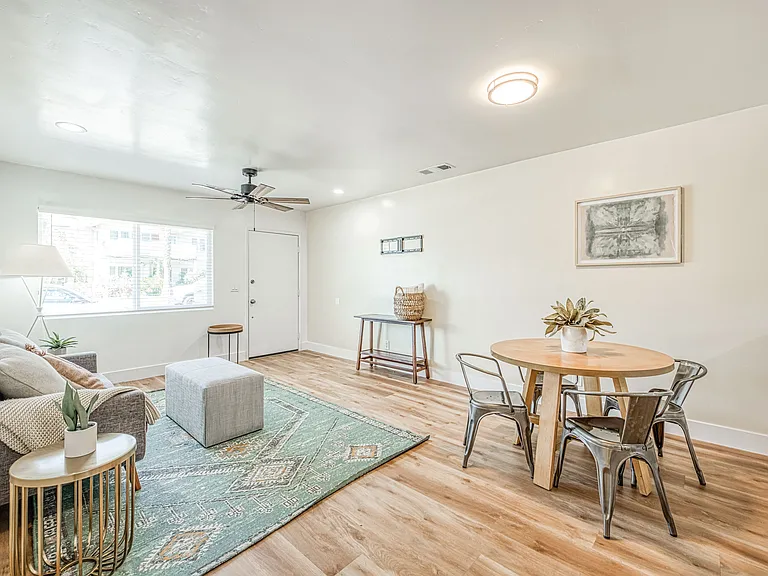 Living Room is fully Furnished with Sofas, Area Rug, Dining Table, Scenic Picture on the Wall and Decor Tables.