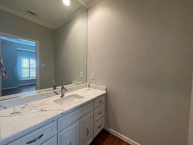 Bathroom featuring vanity, ornamental molding, and dark wood finished floors