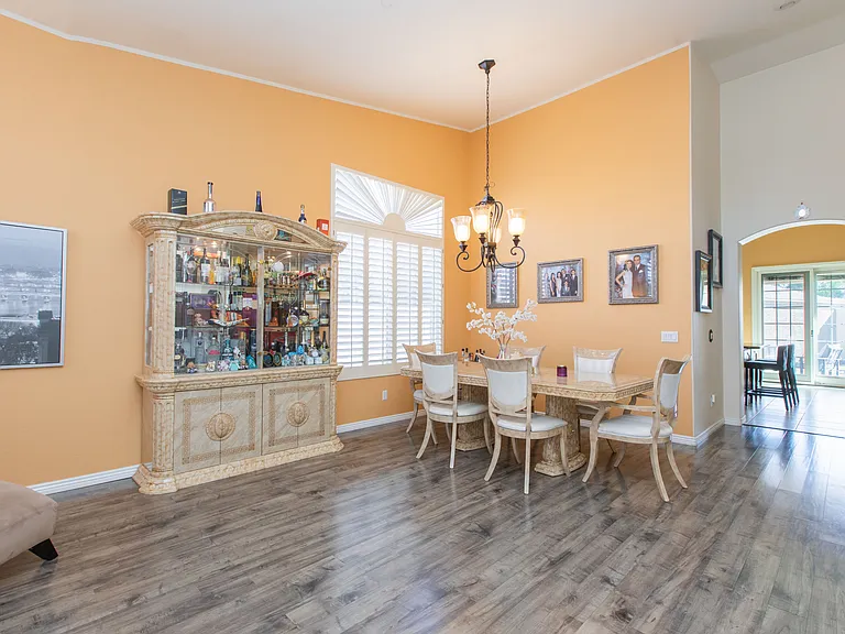 Spacious dinning & living room featuring vintage oak wood-look flooring, vaulted ceilings & window wood shutters