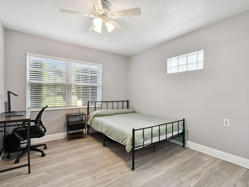 Full size cozy bed, with end table, light, office desk, chair and light as well as storage container under the bed.