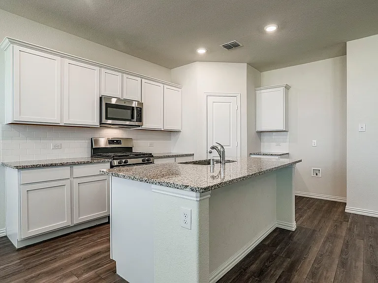 Kitchen with white cabinetry, stainless steel appliances, sink, and a center island with sink