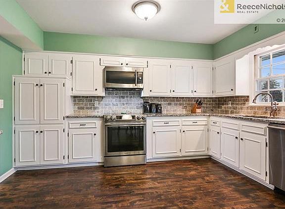 Kitchen also has stone tile subway backsplash and hardwood floors.
