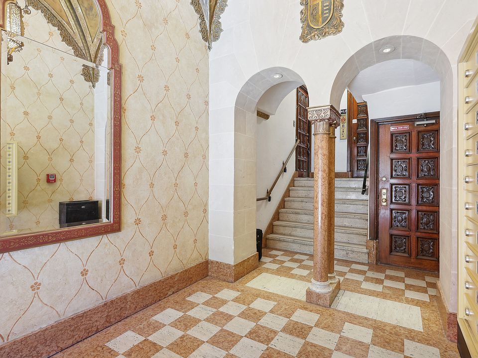 Hallway with a high ceiling and a large mirror with a wooden door