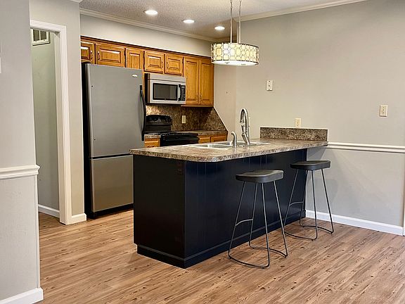 Pullman style kitchen with bar seating and full pantry. Refrigerator, microwave, dishwasher, electric range, double sink with disposal.