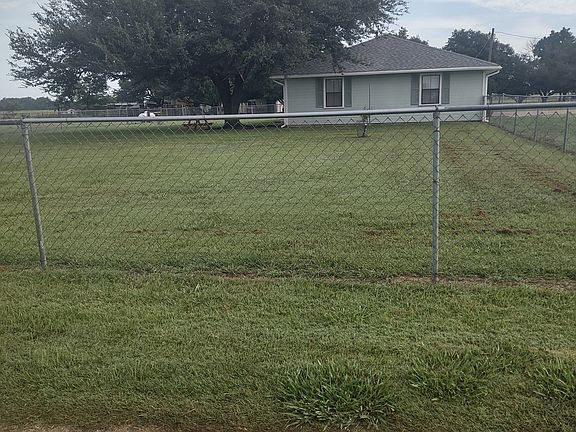 South side of house showing live oak tree in back and large fenced yard.